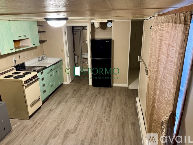 A kitchen with a refrigerator, sink, and cabinets.