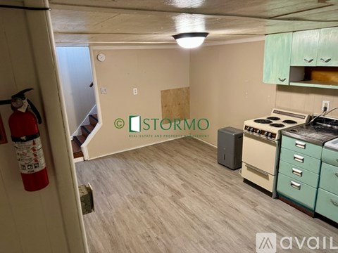 A kitchen with a stove, oven, and cabinets in a room with a fire extinguisher on the wall.