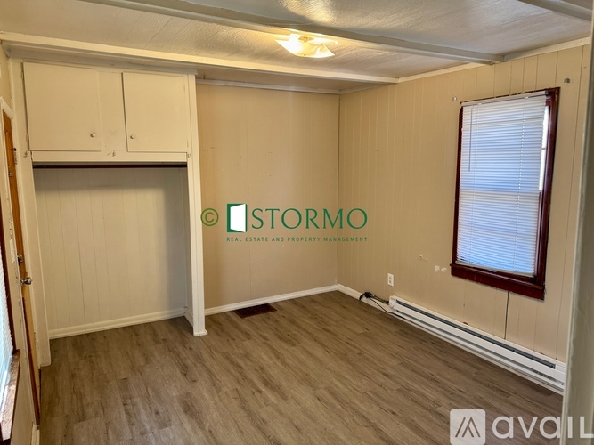 A room with wooden flooring and a window with blinds.