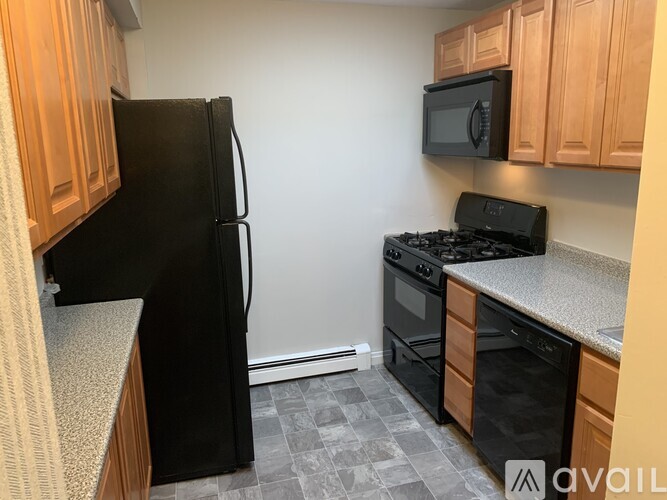 A kitchen with black appliances and wooden cabinets.