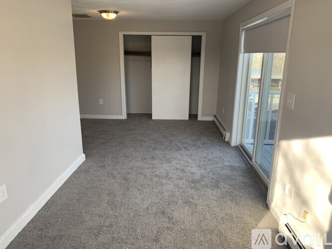 A spacious room with a carpeted floor and a doorway leading to another room.