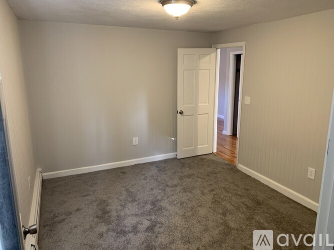 A room with a carpeted floor and a doorway leading to another room.