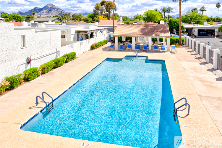 A large outdoor swimming pool with a blue tiled edge and a white building in the background.