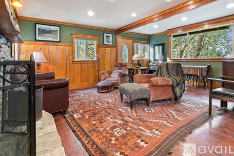 A living room with a rug on the floor and a fireplace on the left.