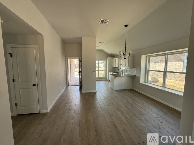 A spacious room with wooden flooring and a chandelier.