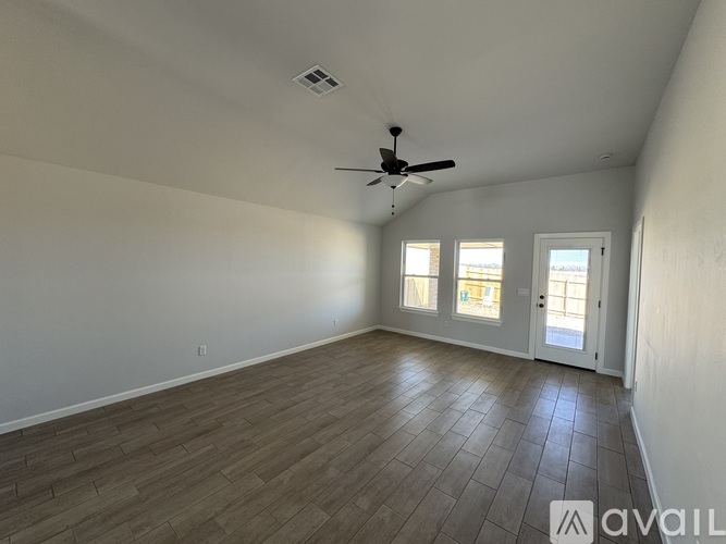 A room with a ceiling fan and wooden flooring.