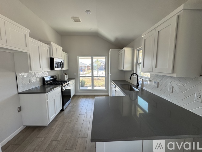 A kitchen with white cabinets and a black countertop.