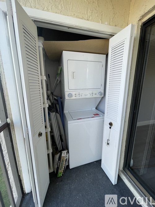 A white washing machine is in a small space between two doors.