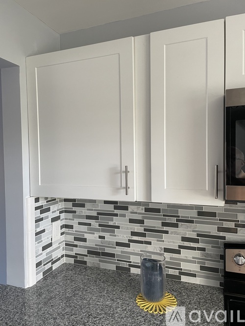 A kitchen with white cabinets and a grey countertop.
