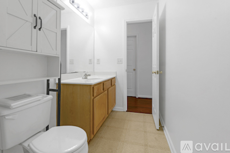 A bathroom with a toilet, sink, and cabinets.
