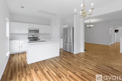 A kitchen with white cabinets and a wooden floor.