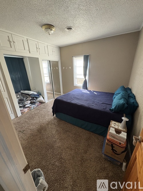 A bedroom with a bed, nightstand, and window.