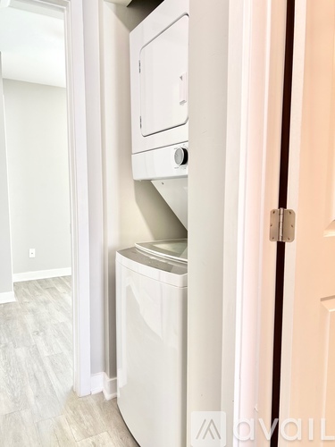 A white dishwasher is in a narrow space between a door and a wall.