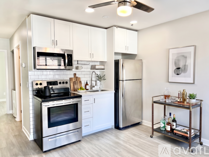 A modern kitchen with a stainless steel refrigerator and a bar cart with bottles on it.