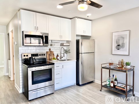 A modern kitchen with a stainless steel refrigerator and a bar cart with bottles on it.