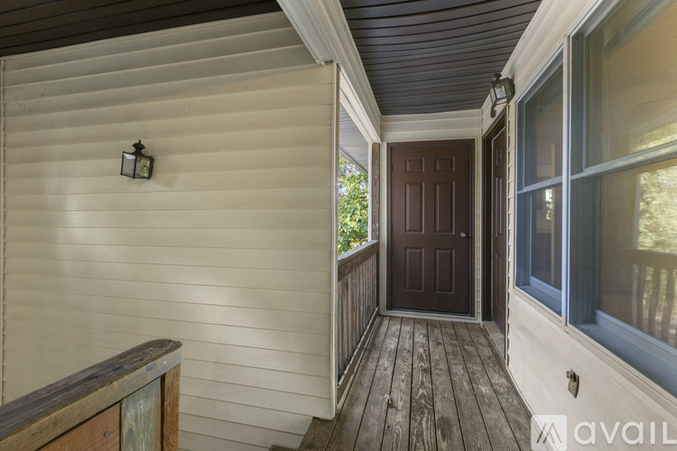 A wooden deck with a brown door and a lantern hanging on the wall.