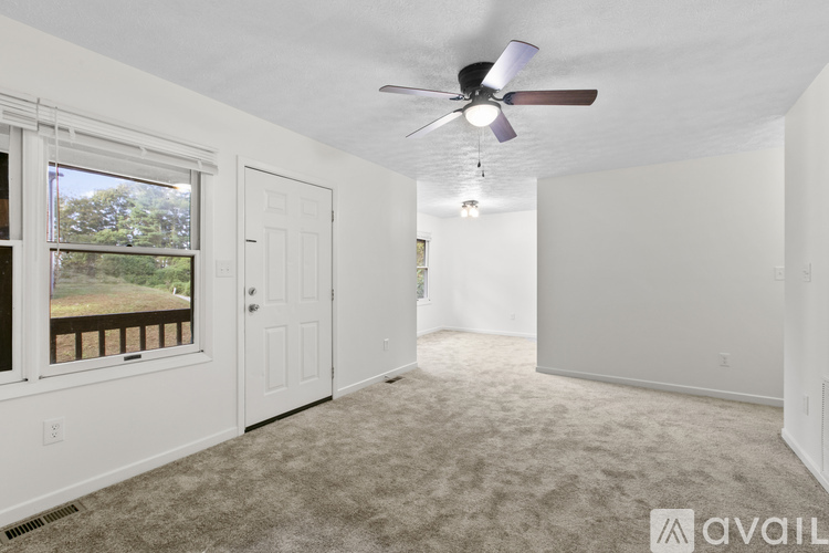 A spacious room with a ceiling fan and carpeted floor.