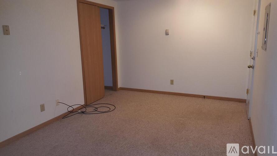 A room with a carpeted floor and a wooden door.