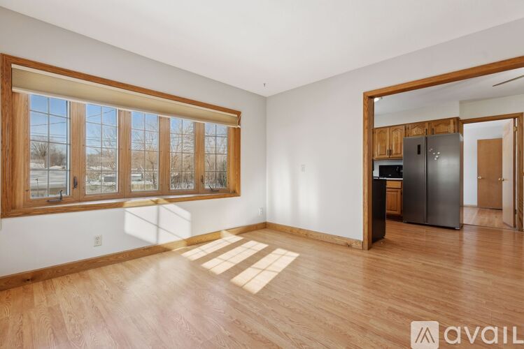 A spacious room with wooden floors and a large window with a view of a snowy landscape.