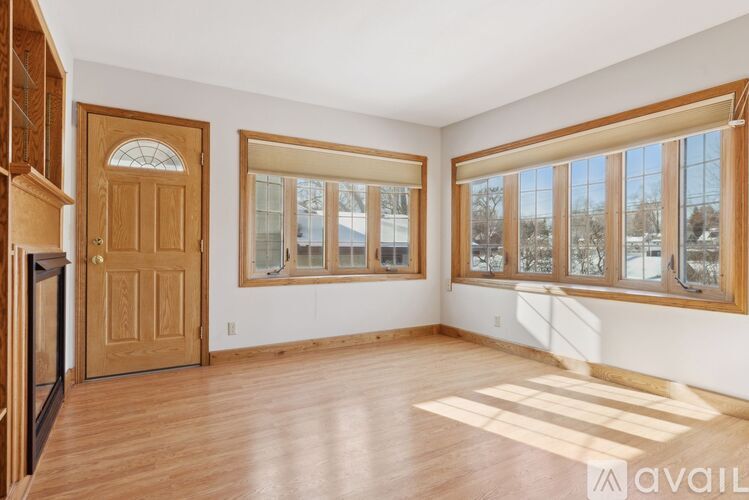 A room with wooden floors and a large window with a view of trees outside.