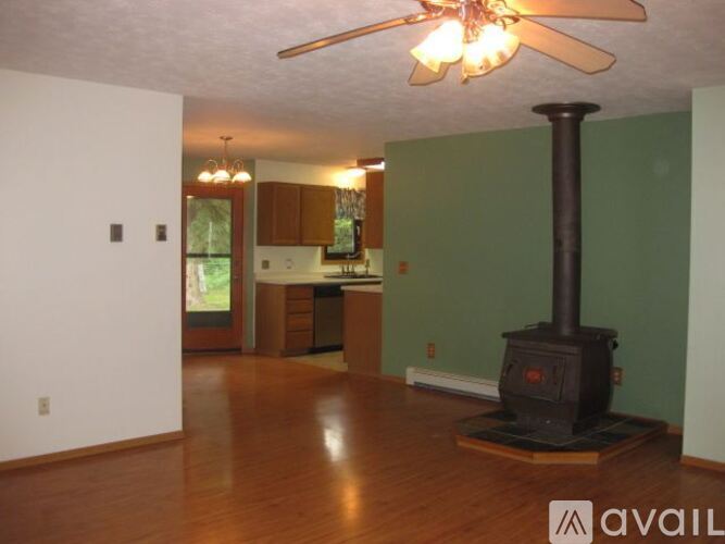 A wood burning stove in a living room with a ceiling fan.