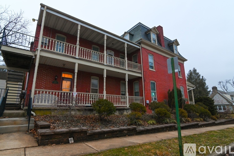 A red house with a balcony and a green pole in front.