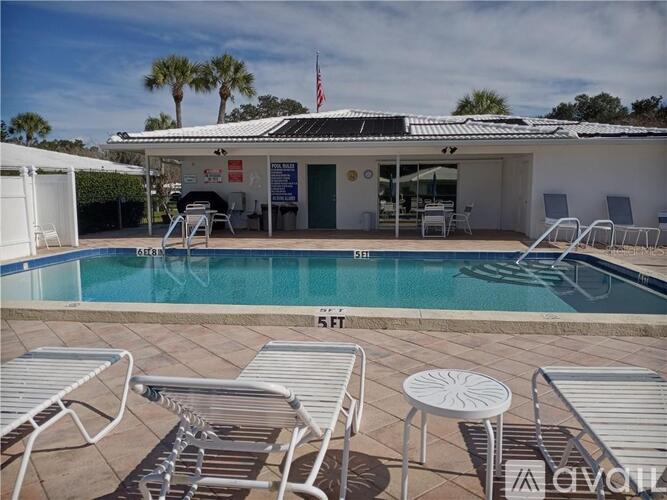 A pool with chairs and a building in the background.