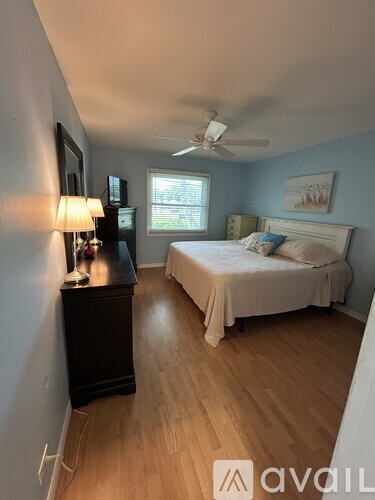 A bedroom with a bed, dresser, and window.