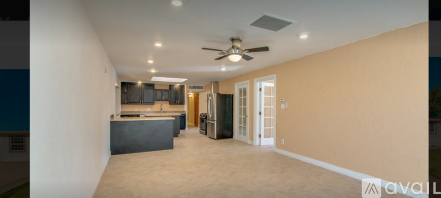 A spacious room with a kitchen area and a ceiling fan.