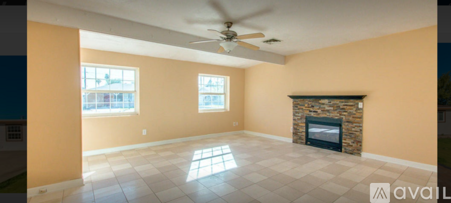 A living room with a fireplace and a ceiling fan.