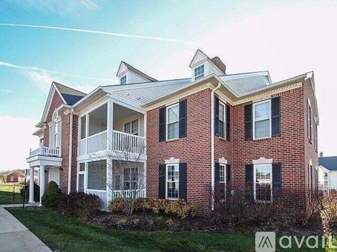 A red brick house with a white porch and a sign that says "available".