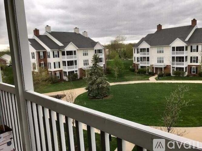 A view from a balcony overlooking a green lawn and two white buildings.