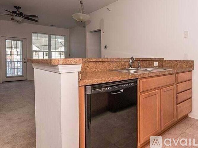 A kitchen with a black dishwasher and wooden cabinets.