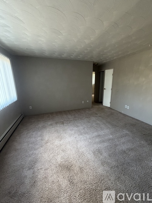 A room with a carpeted floor and a textured ceiling.