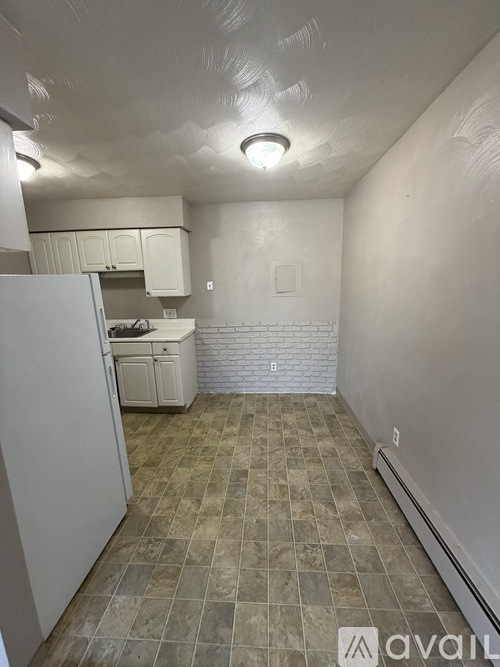 A kitchen with a refrigerator, sink, and cabinets.