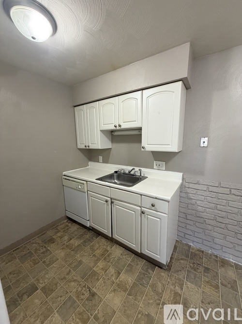 A kitchen with white cabinets and a tiled floor.
