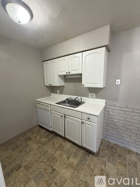 A kitchen with white cabinets and a tiled floor.