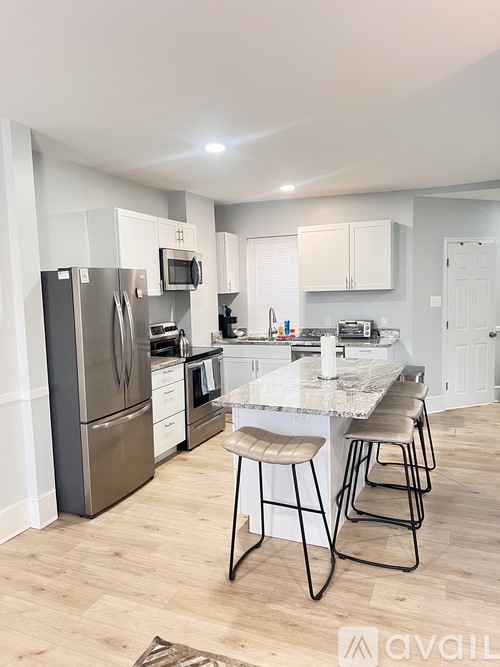 A kitchen with a refrigerator, oven, and bar stools.