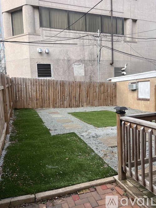 A backyard with a wooden fence and a small grassy area.