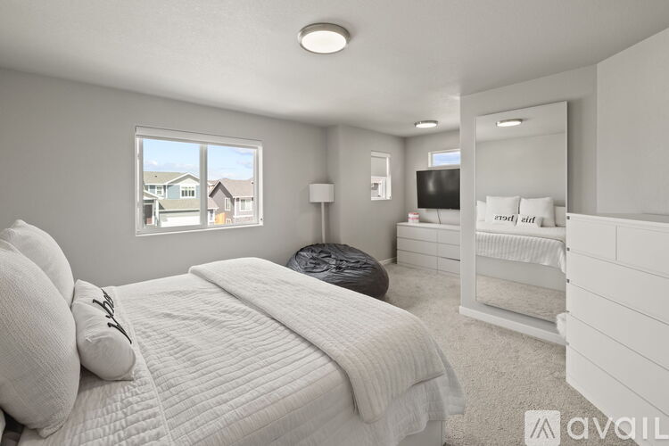 A bedroom with a large bed and a window overlooking a residential area.