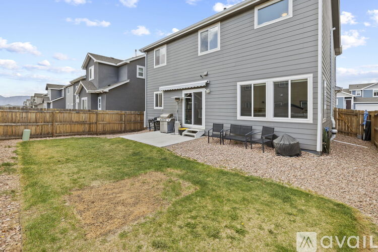 A house with a grey exterior and a patio area with a table and chairs.