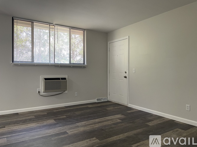A room with a window, a door, and a wall-mounted air conditioner unit.