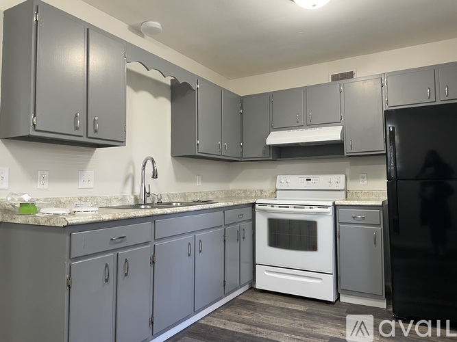 A kitchen with a white stove top oven and a black refrigerator.