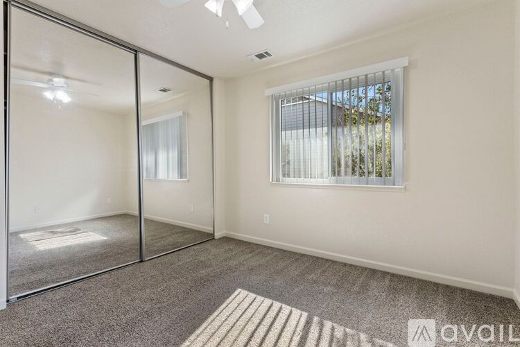 A room with a carpeted floor, a sliding glass door, and a window with blinds.