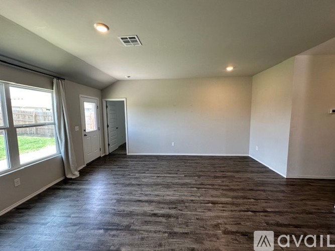 A spacious room with a dark wood floor and white walls.