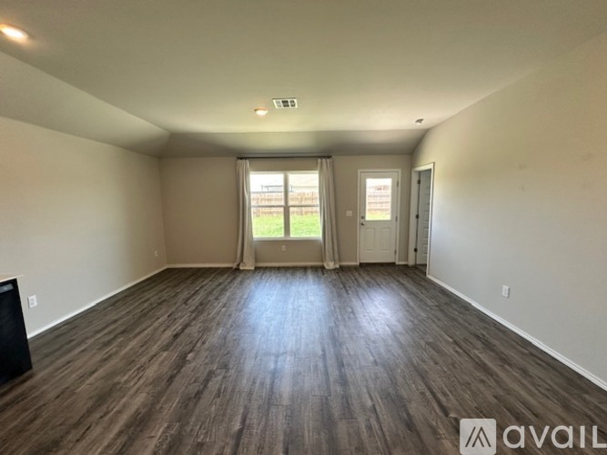 A spacious room with wooden flooring and a large window.