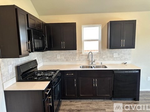 A kitchen with black cabinets and appliances.