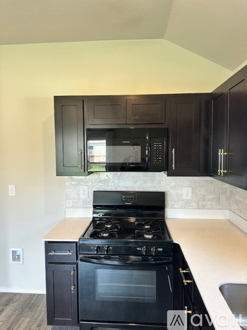 A kitchen with a black stove and microwave above it.