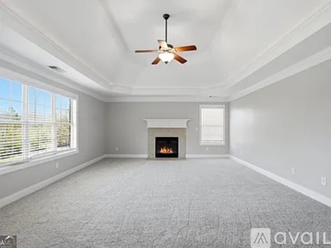 A spacious living room with a fireplace and a ceiling fan.