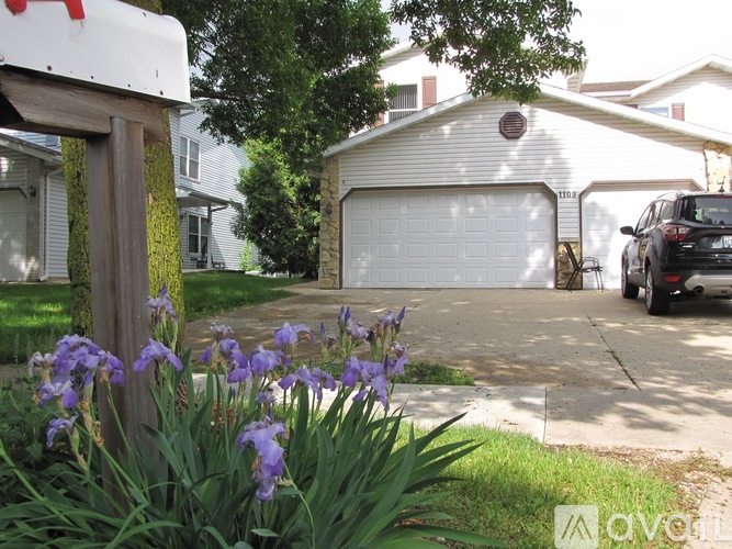 A white garage door is in the middle of a driveway.